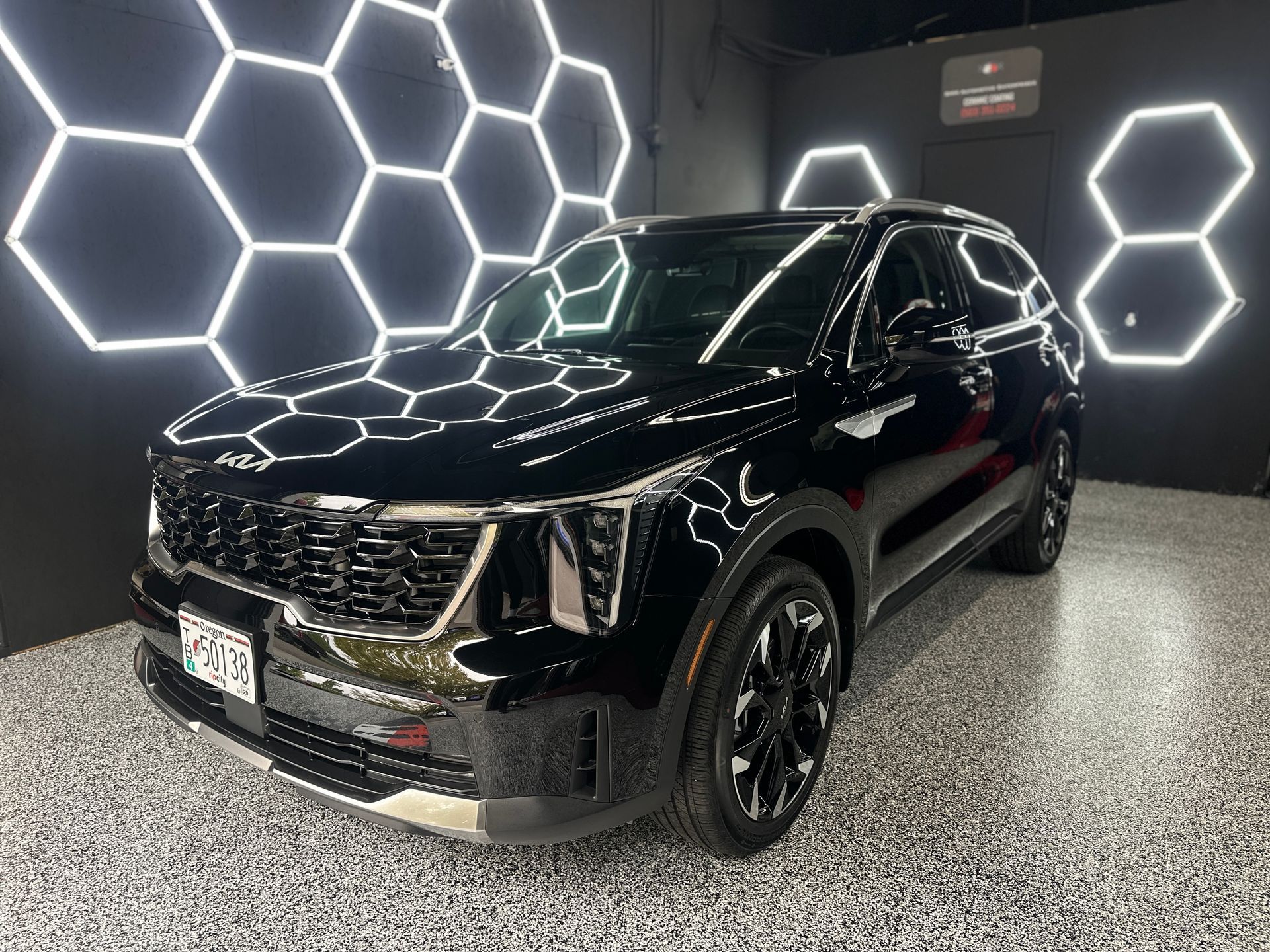 Black SUV displayed indoors under bright hexagonal lights on a polished floor