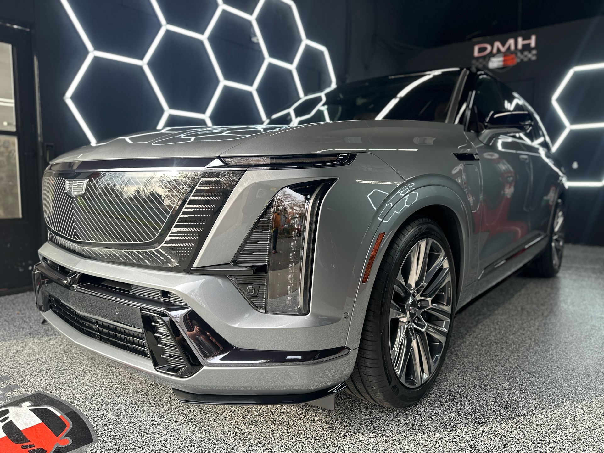 Gray Cadillac Escalade in a showroom with a honeycomb-lit wall backdrop
