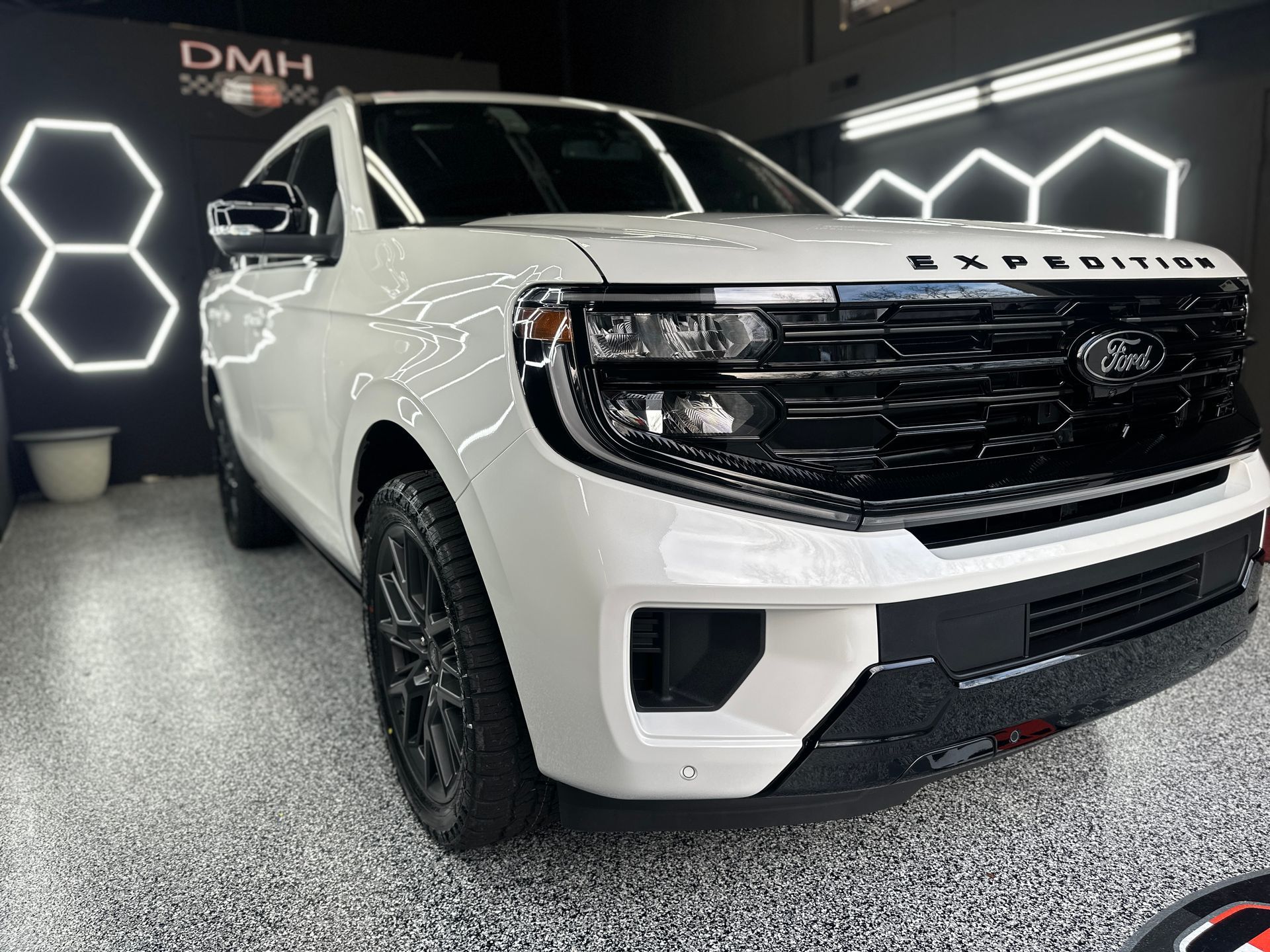 White Ford pickup truck in a showroom, front three-quarter view with black grille and wheels