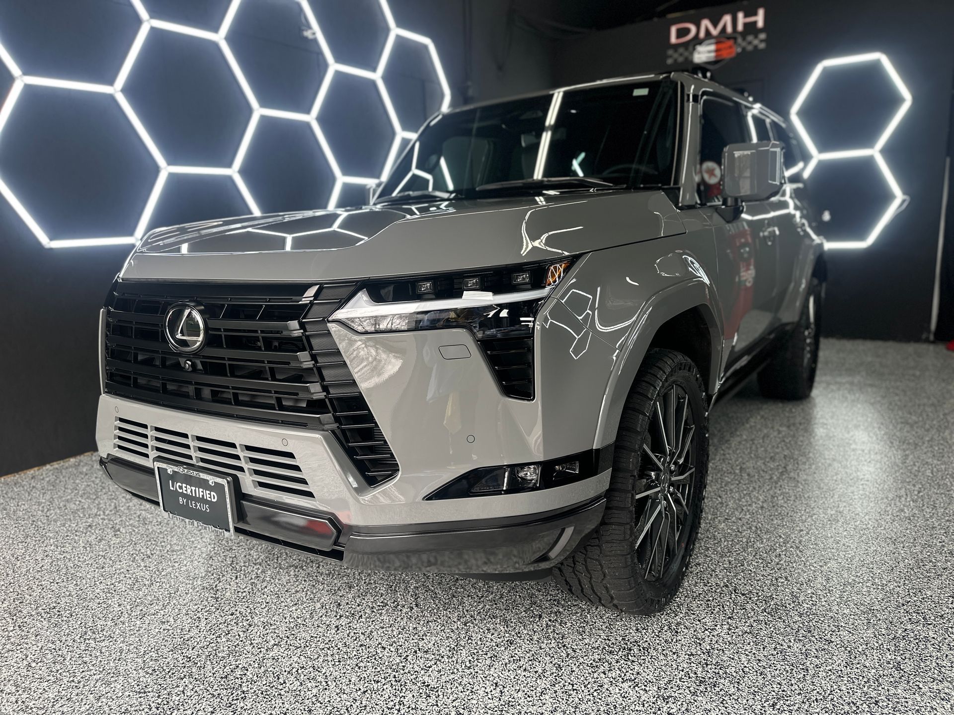 Gray Lexus SUV displayed indoors against a hexagonal LED wall backdrop.