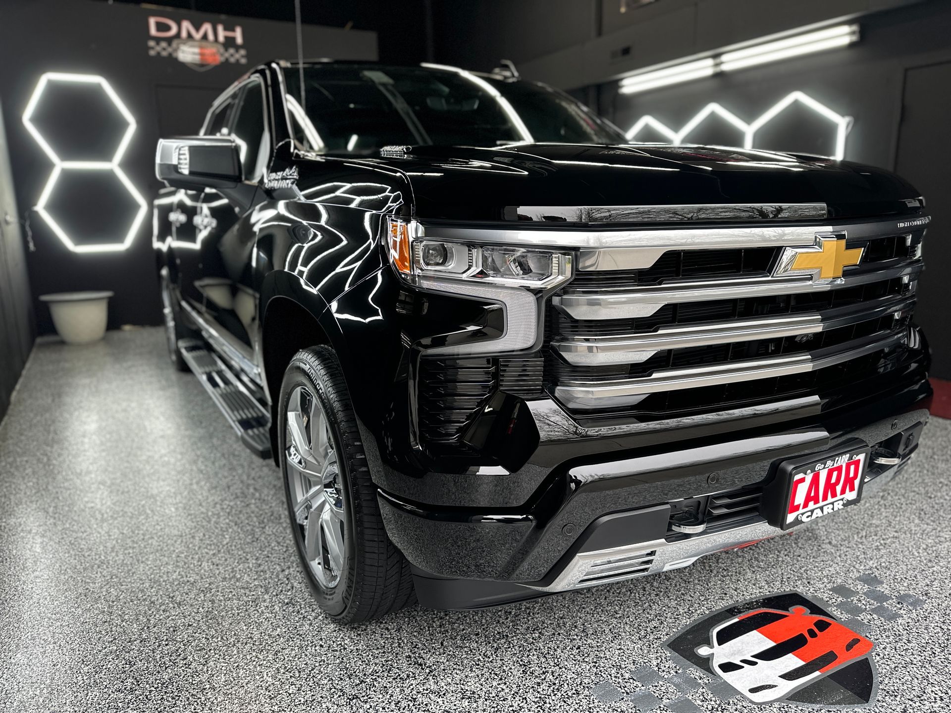 Black Chevrolet pickup truck in a showroom with bright hexagonal wall lights