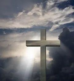 White cross silhouetted against a cloudy sky with sun rays shining through