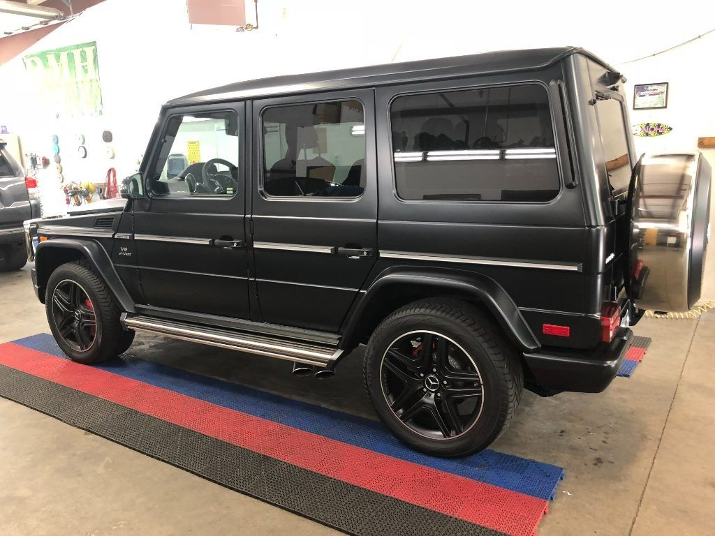 Black Mercedes G-Class SUV parked indoors on a red and blue floor mat