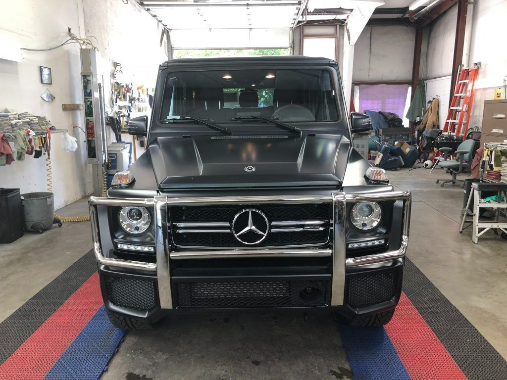 Black Mercedes-Benz G-Class SUV inside a garage, front view on a lift mat.