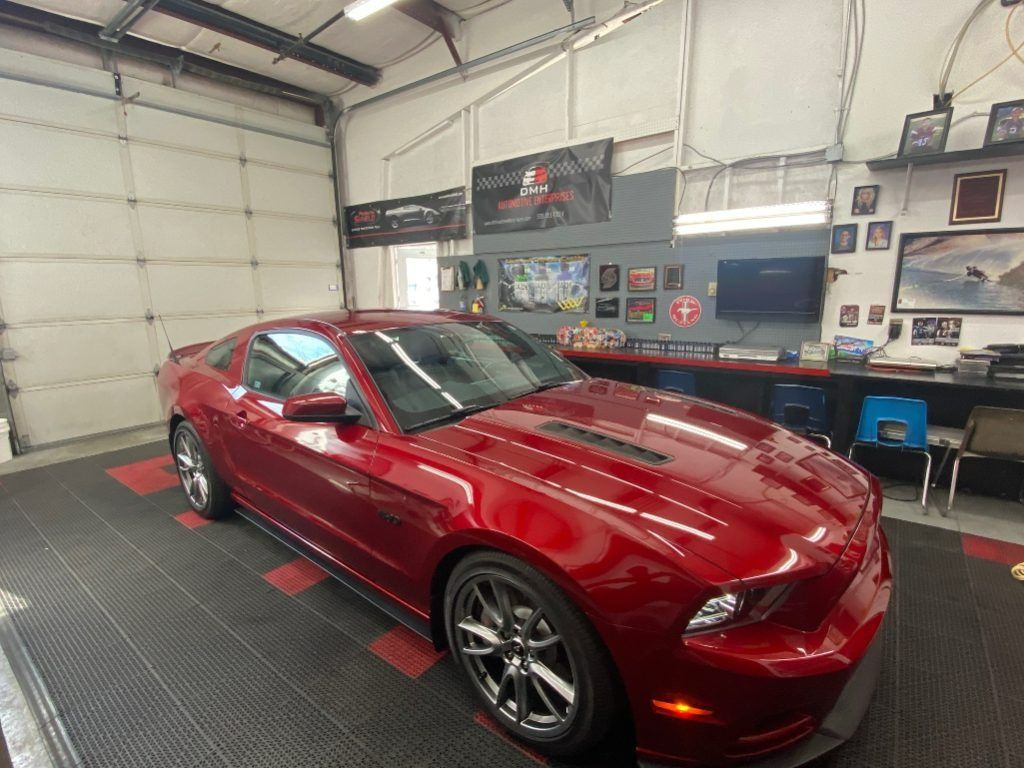 Red sports car in a garage workshop with tools and posters on the walls.