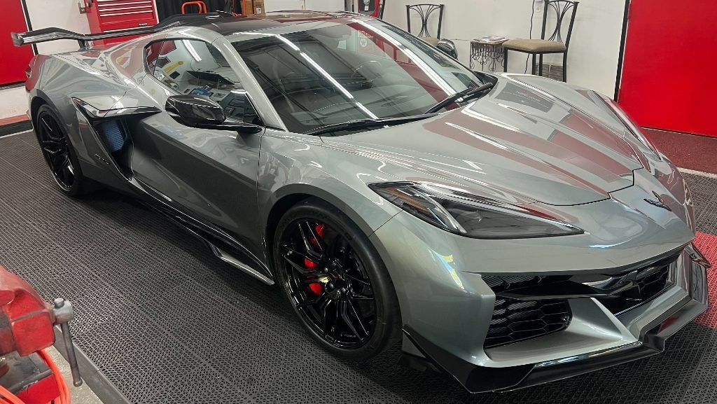 Gray sports car with black wheels displayed indoors on a showroom floor