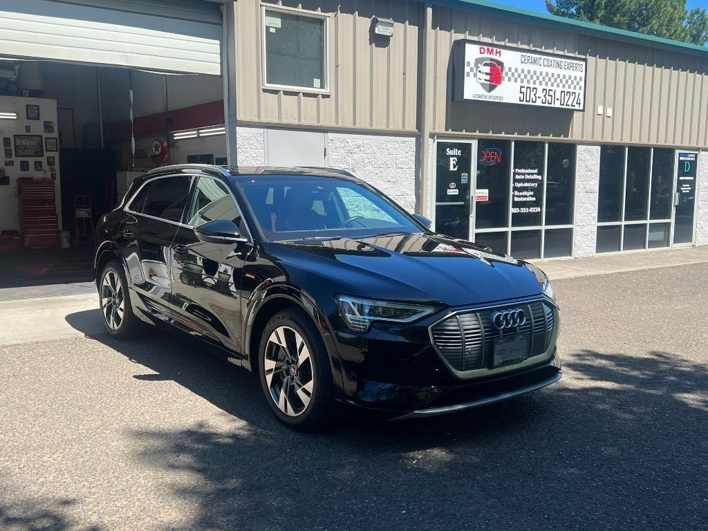 Black SUV parked outside an auto shop on a sunny day.