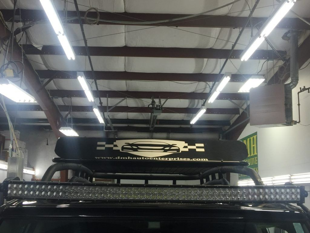 Off-road vehicle in a garage with bright overhead lights and a roof rack visible