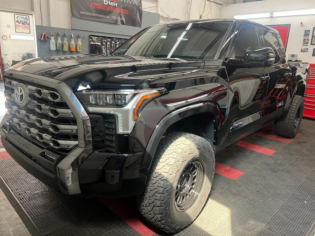 Black lifted pickup truck in a garage, viewed from the front-left side.