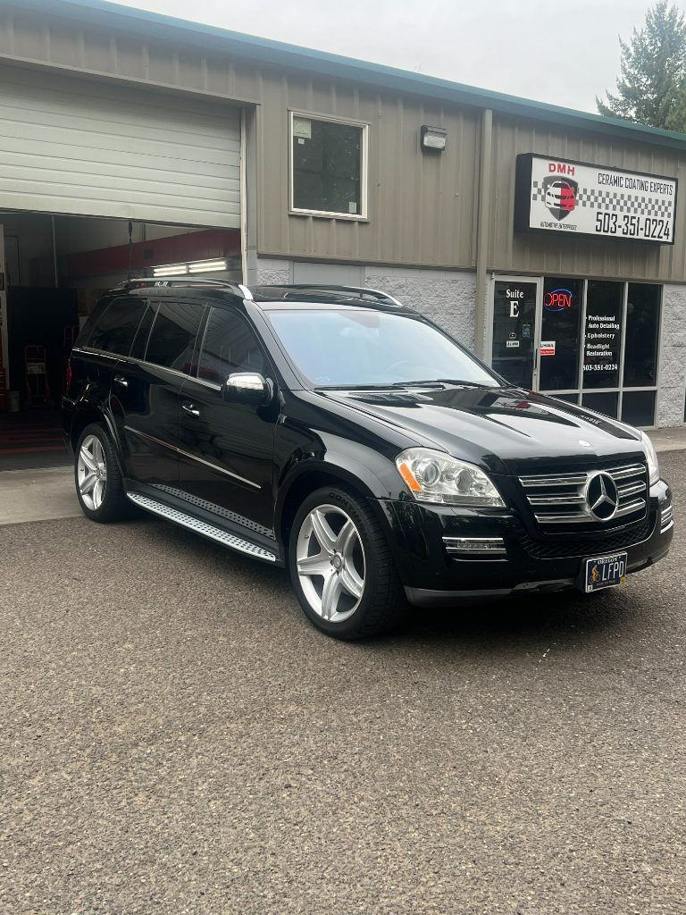 Black Mercedes SUV parked outside a shop with a garage door and sign