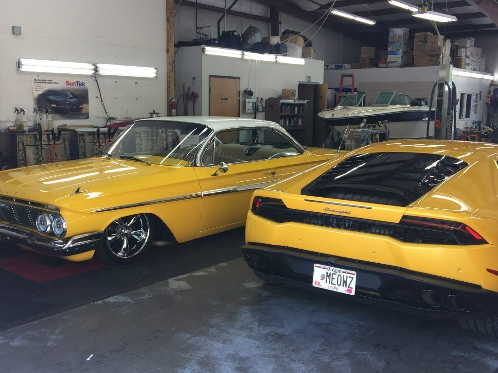 Two yellow classic sports cars parked inside an auto shop, one viewed from the front and one from the rear.