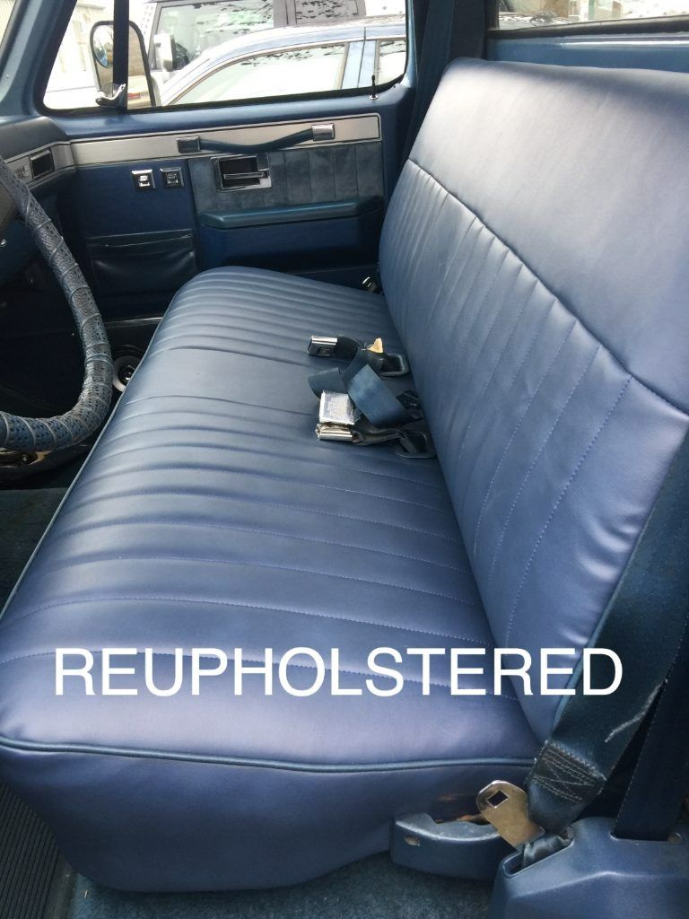 Reupholstered blue vinyl bench seat in a vehicle interior with a small tool on it