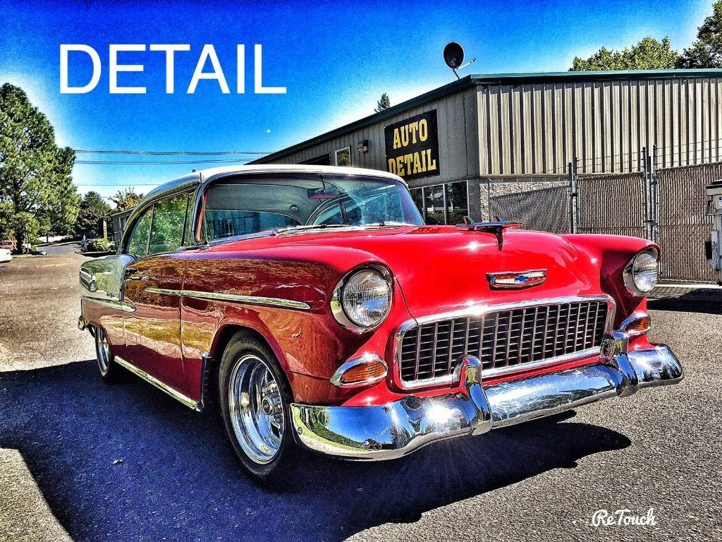 Red classic 1950s car parked outdoors beside a corrugated metal building.