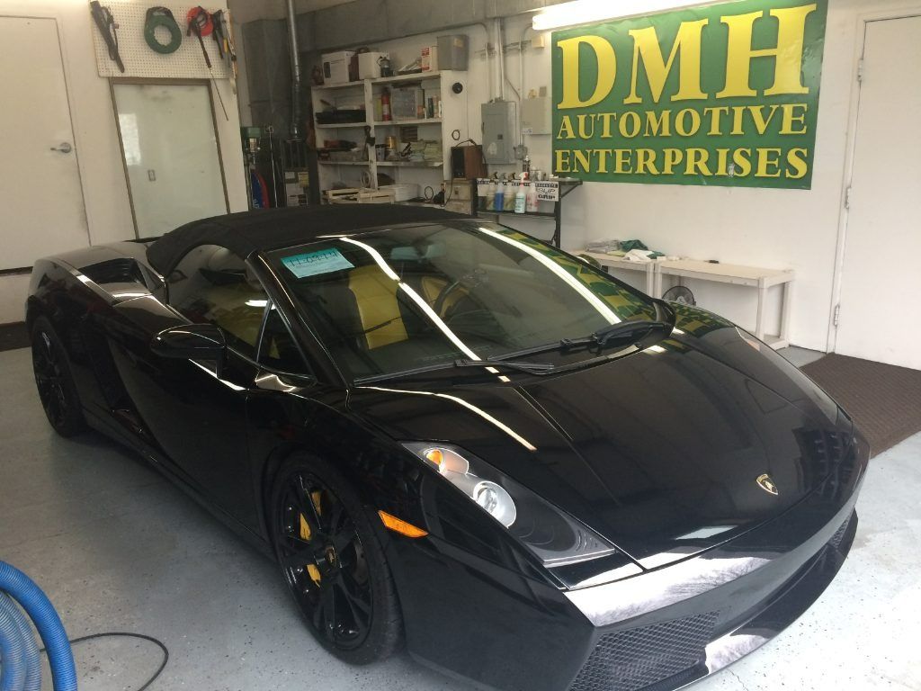 Black sports car in an automotive shop with a DMH Automotive Enterprises sign in the background