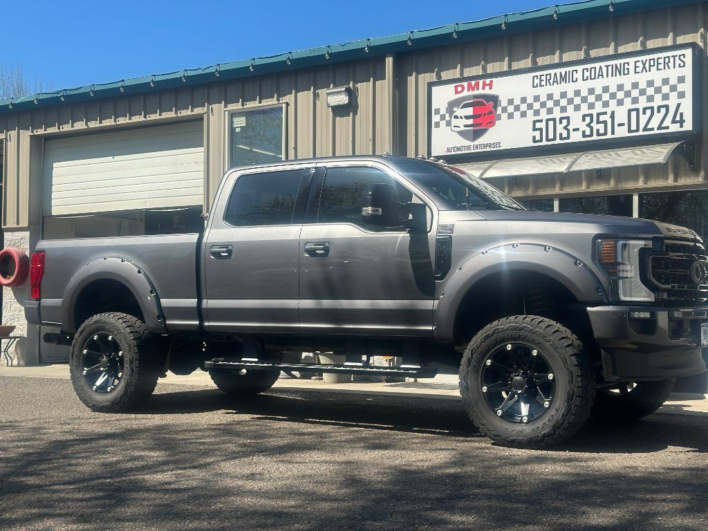Lifted gray pickup truck parked outside a shop with a sign above the building.