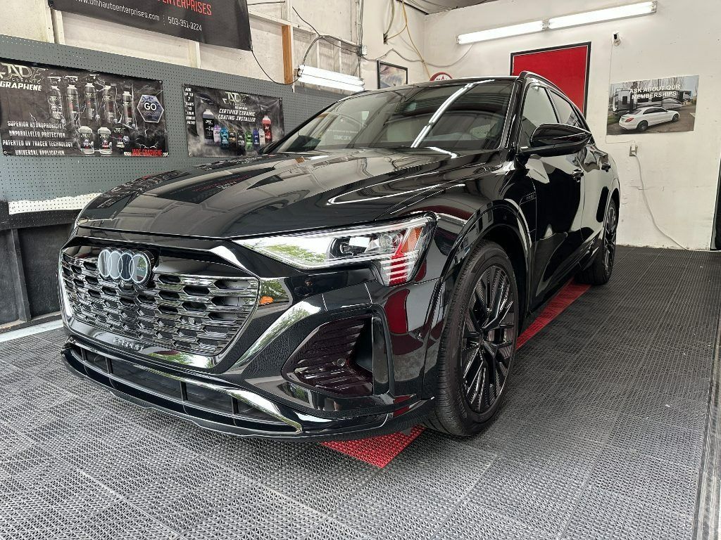 Black SUV in a car detailing garage, viewed from the front-left.