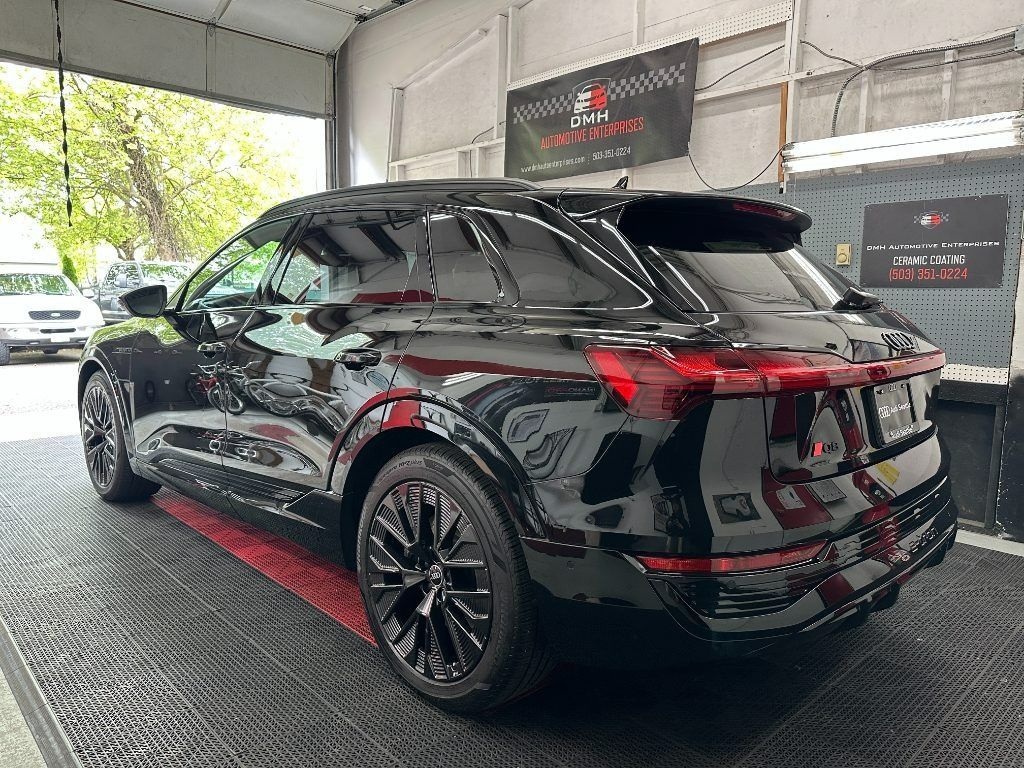 Black SUV with red accents parked indoors under a covered carport.