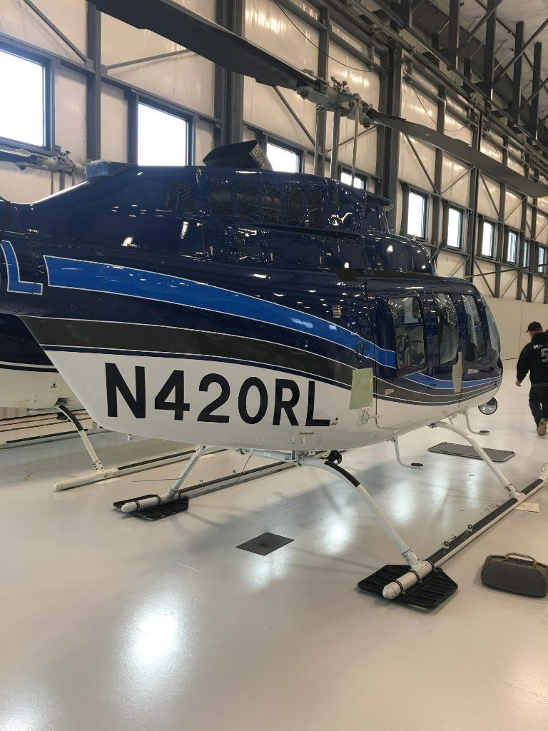 Blue and white helicopter on display in a hangar, tail number N420RL visible.