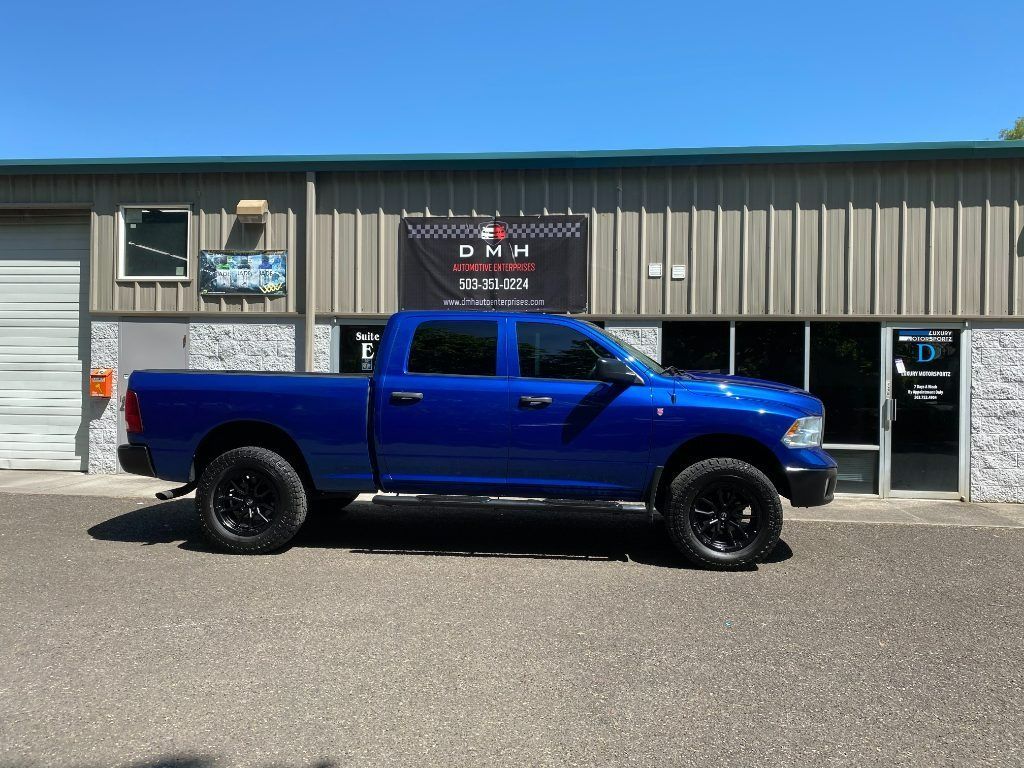 Blue pickup truck parked outside a metal building with a sign above the entrance