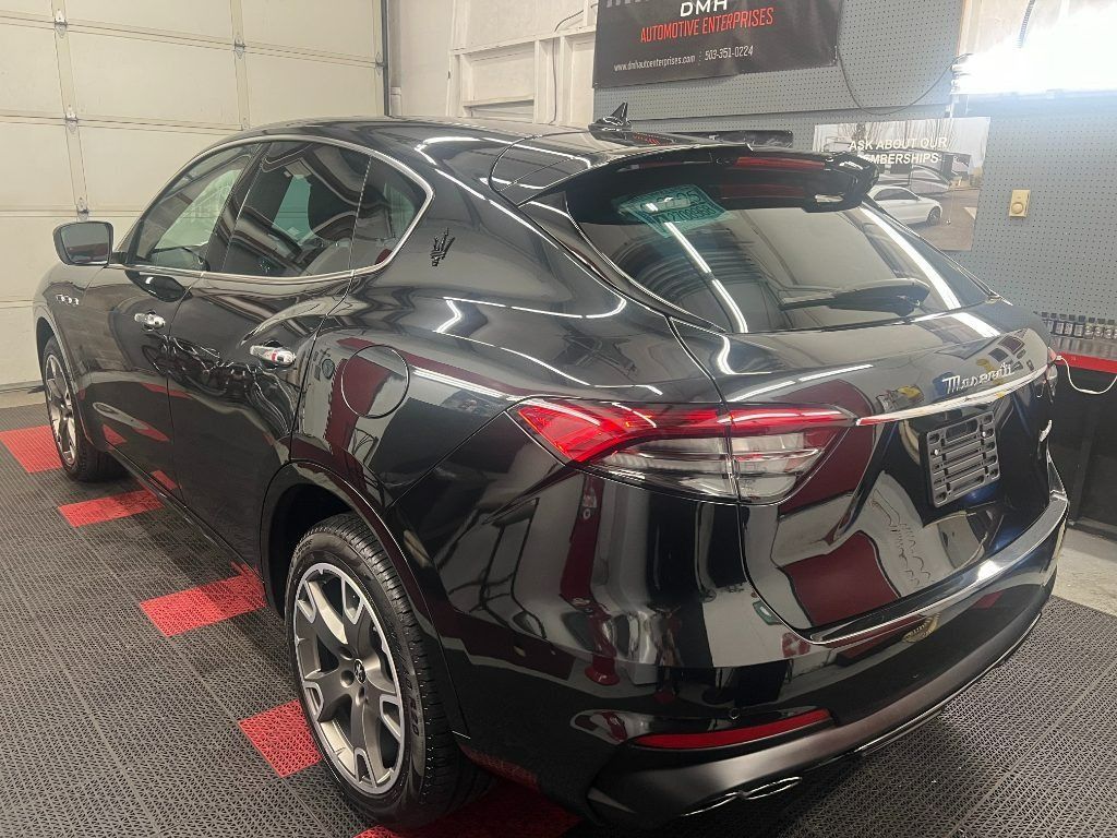 Black SUV in a garage, viewed from the rear-left side on a red-and-black checkered floor.