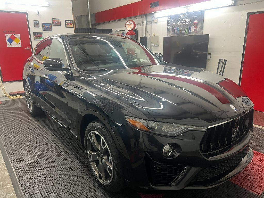Black Maserati SUV in a car wash bay, seen from the front-left side.