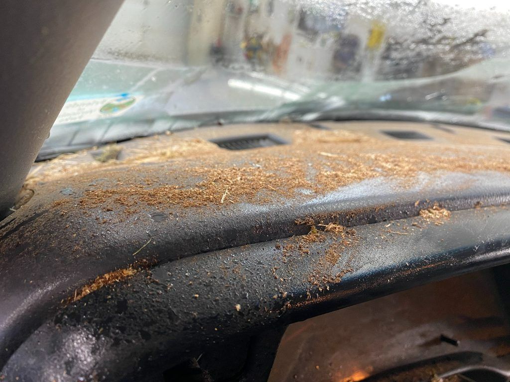 Dust-covered car dashboard seen through a fogged windshield in rainy weather