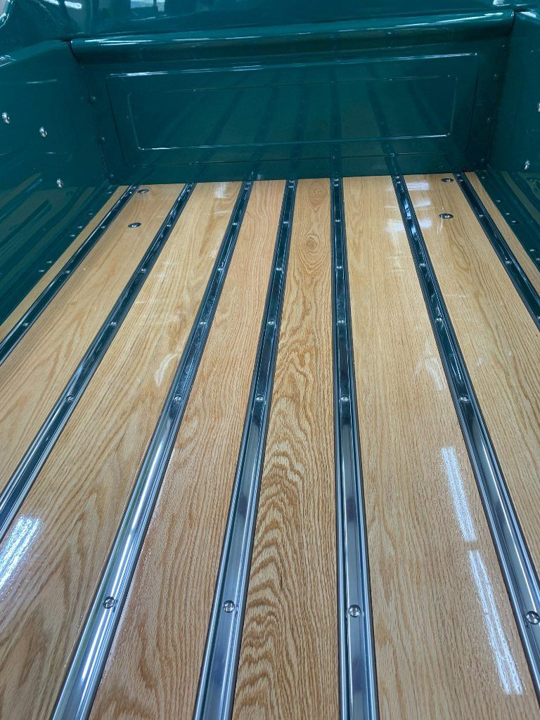 Wood-paneled truck bed with shiny metal rails and teal sidewalls