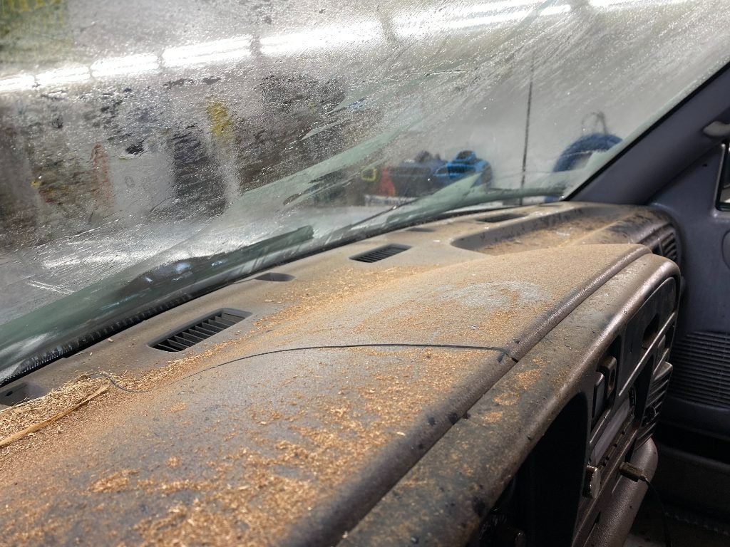 Dusty car dashboard and windshield covered with orange dust or pollen inside a vehicle