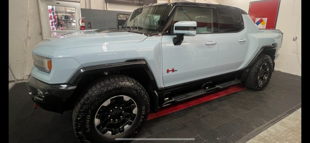 Light blue off-road pickup truck with black roof and wheels displayed indoors on a showroom floor