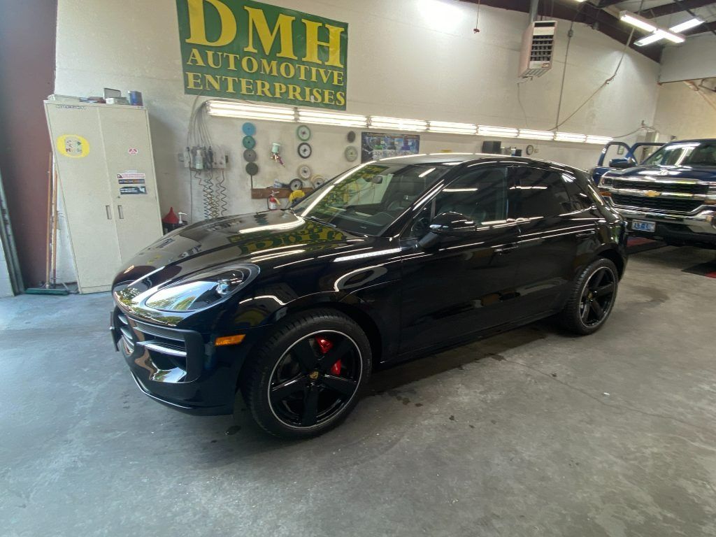 Black SUV with red brake calipers displayed inside an auto dealership showroom.