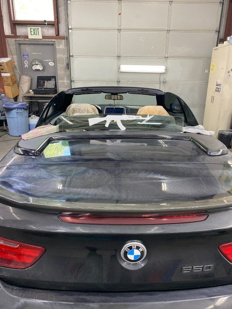 Black BMW convertible parked in a garage, viewed from the rear with the top down