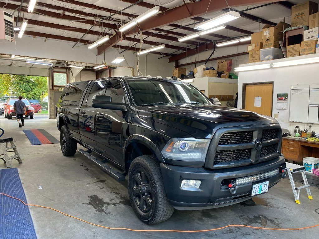 Black pickup truck inside a garage with tools and boxes around it