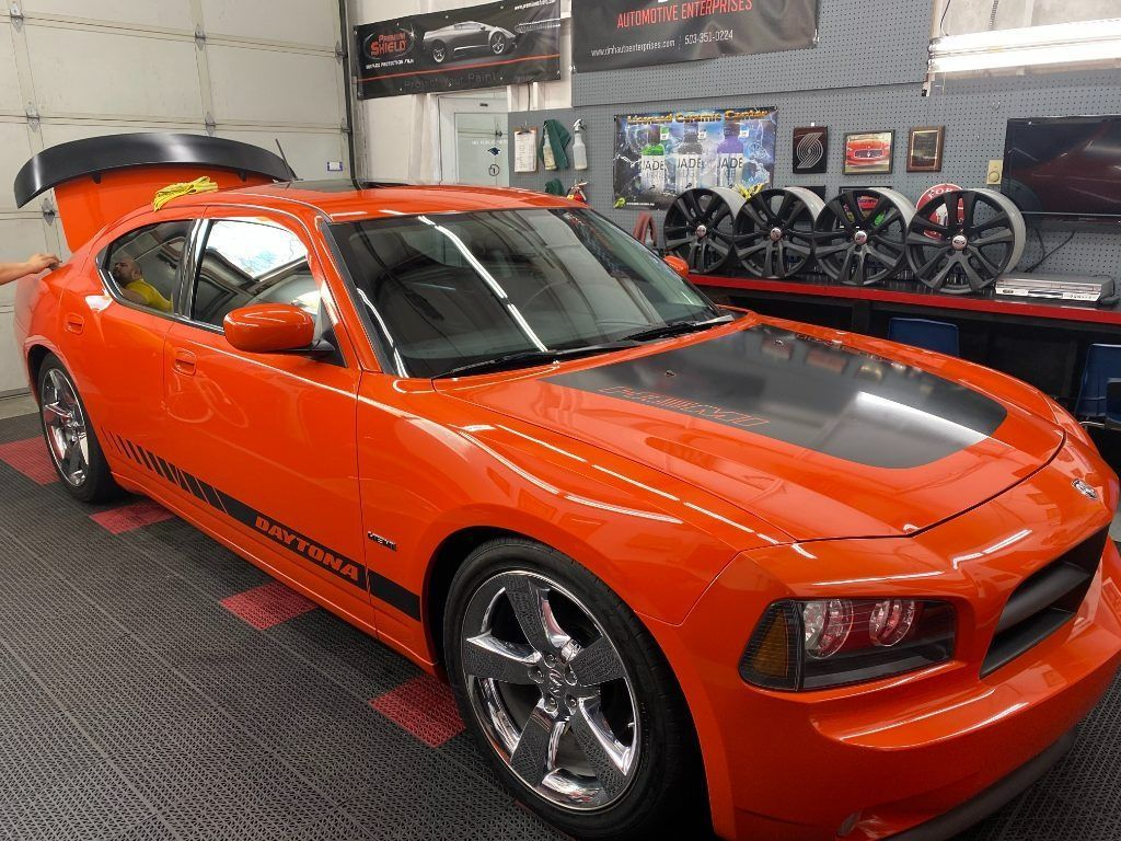 Orange sports car with black hood stripes displayed in an indoor showroom