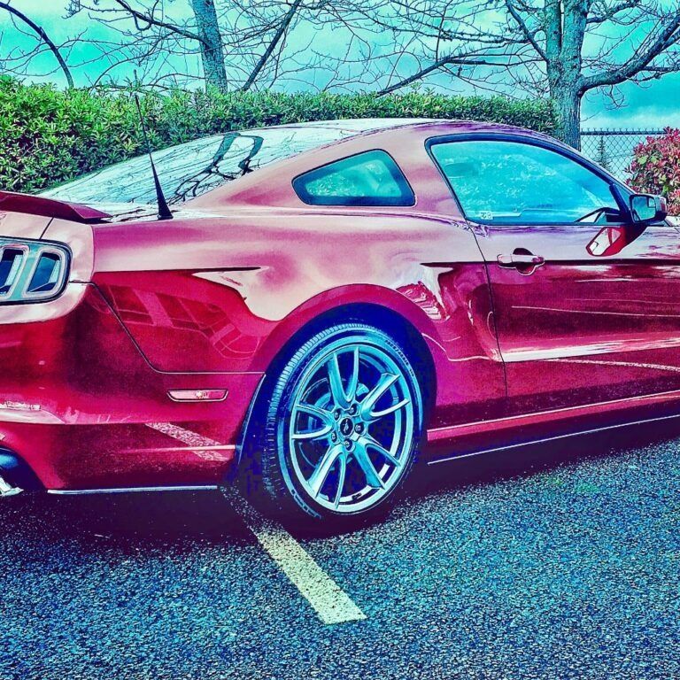 Red sports car parked in a lot, shown from the side under a stylized blue-pink filter.
