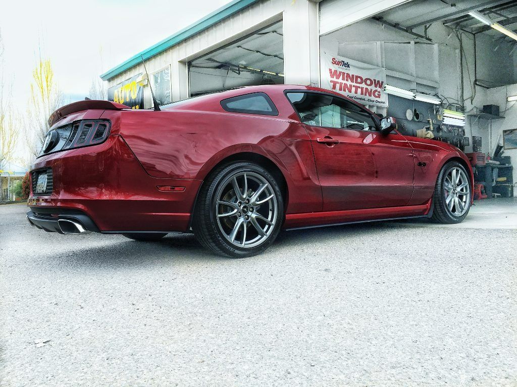 Red sports coupe parked outside a service garage under a canopy