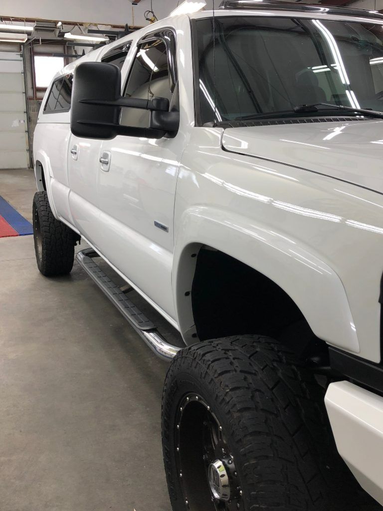 White lifted pickup truck in a garage, shown from the front side.