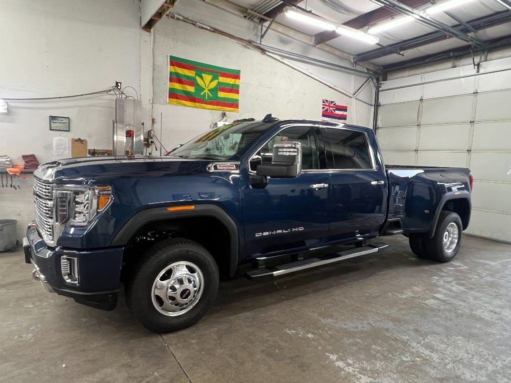 Dark blue pickup truck in a warehouse garage, side view, with flags on the wall.