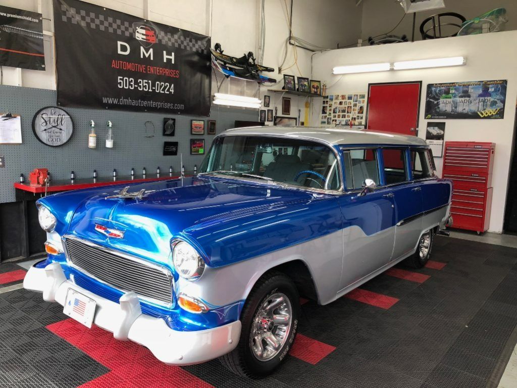 Blue and white classic car parked in a garage workshop with tools and red wall cabinets