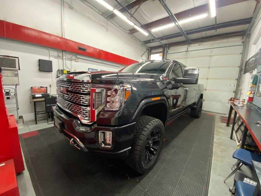 Black pickup truck in a garage bay with bright overhead lights and tools along the walls