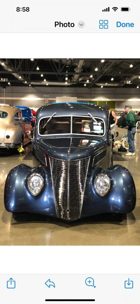 Front view of a vintage blue car on display indoors at an auto show.