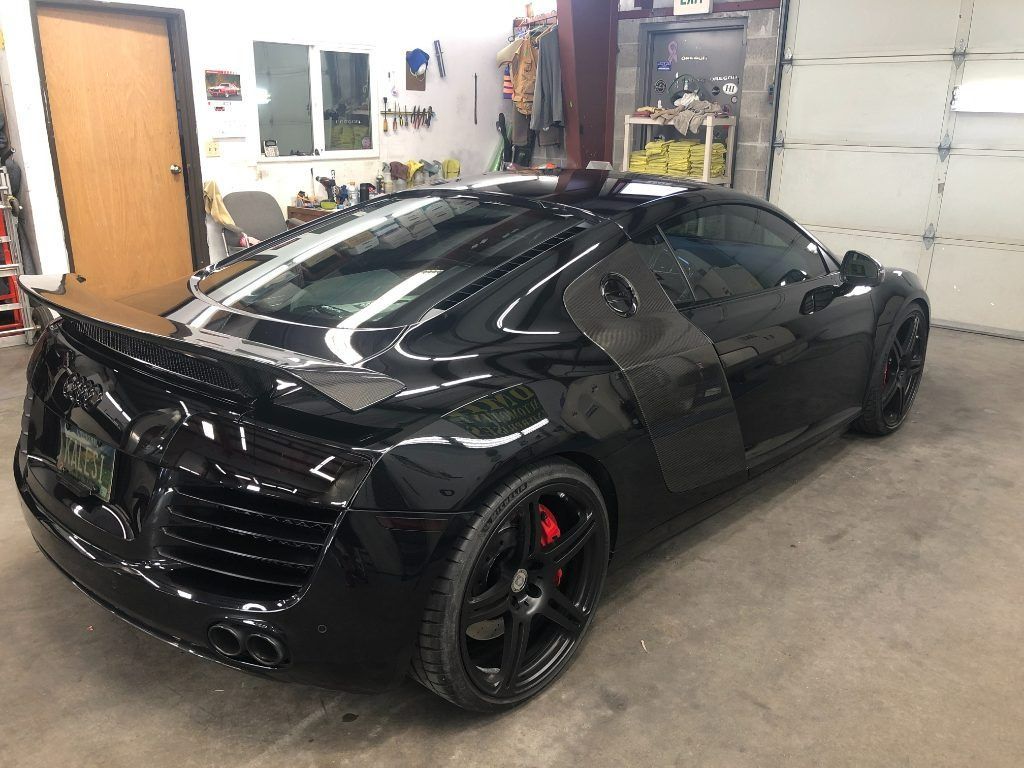Black sports coupe parked inside a garage, shown from the rear-left side.