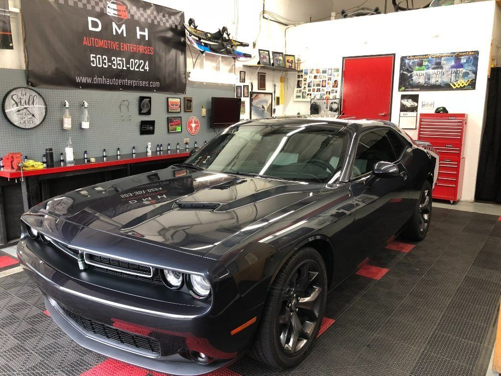 Black Dodge Challenger in an auto shop garage with tools and wall signs