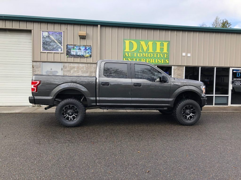 Dark gray pickup truck parked outside DMH Auto Body & Collision shop