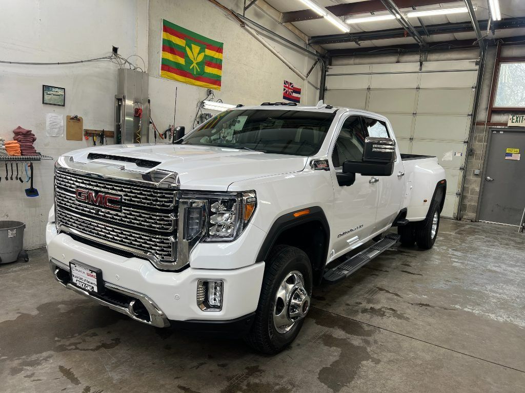 White GMC pickup truck parked inside a garage, angled front-left view with chrome grille and step rails