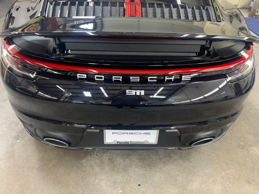 Rear view of a black Porsche sedan with red taillight strip in a garage
