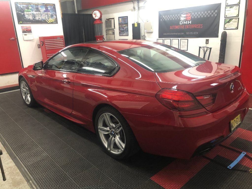 Red sports coupe on a workshop dyno with rear wheels strapped down indoors