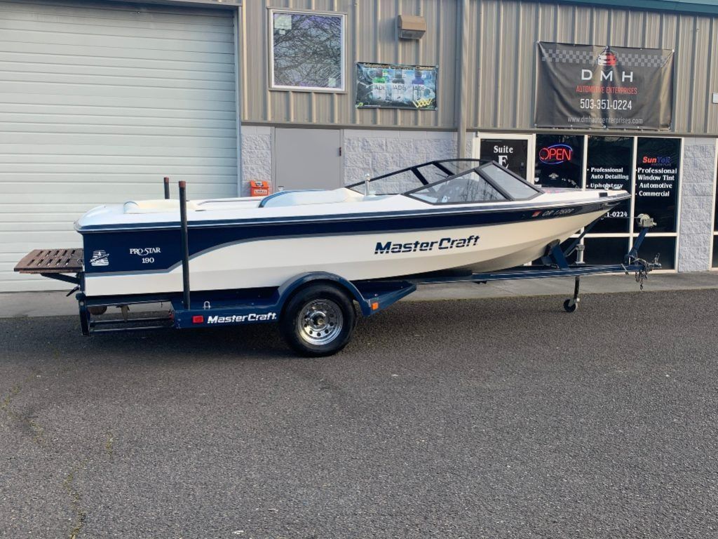 MasterCraft fishing boat on a trailer outside a storefront, with a white hull and black trim