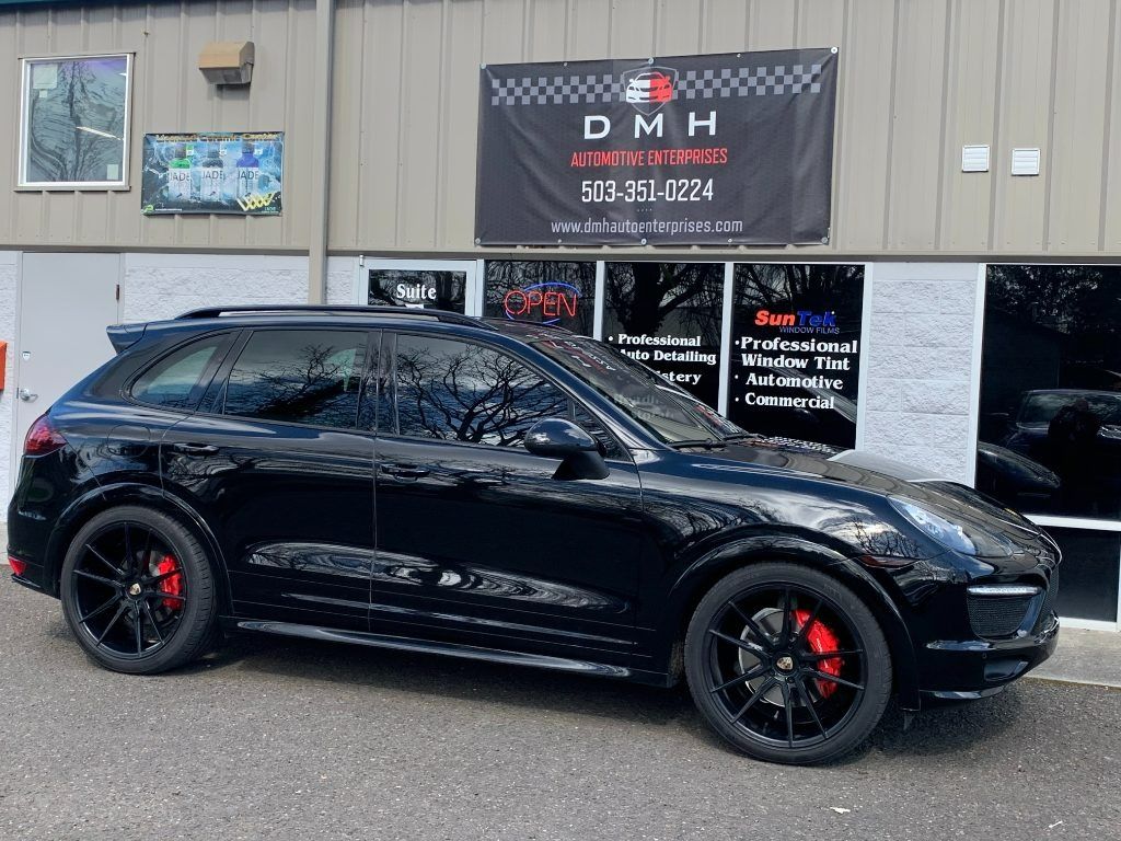 Black SUV parked outside an auto shop with a DMH banner