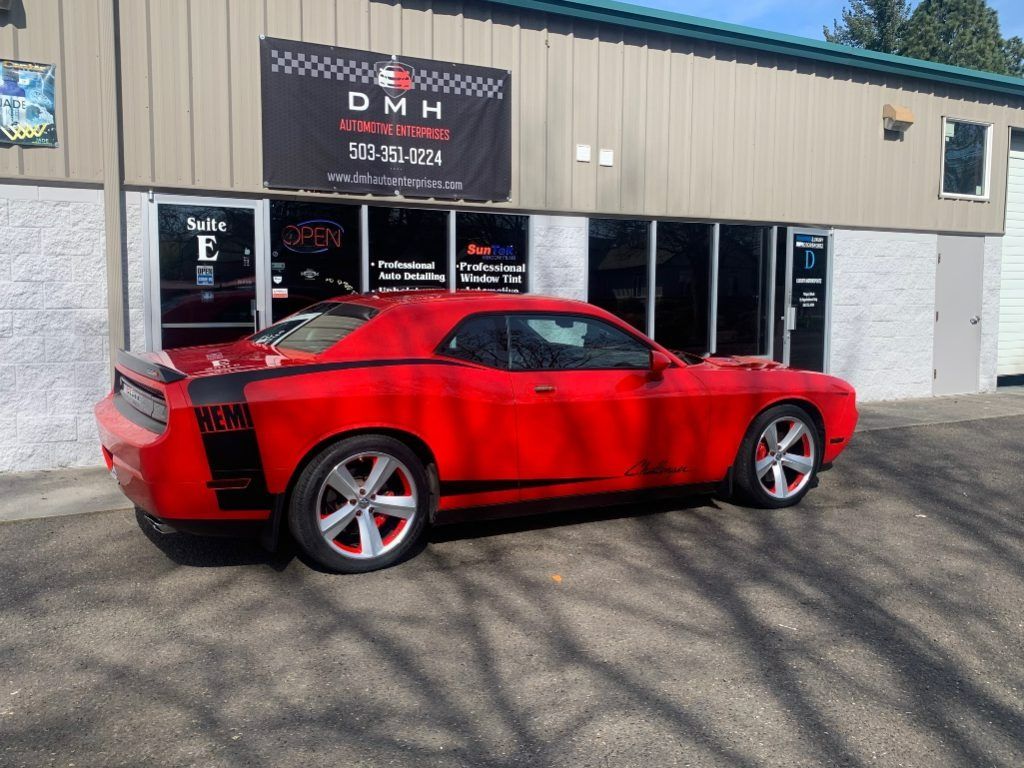Red sports car parked outside a DMH collision repair shop.