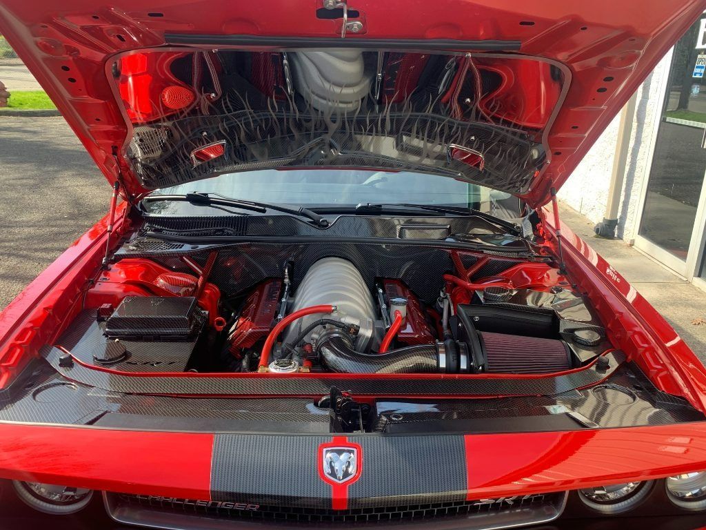 Red car with hood open, showing a modified engine bay and black racing stripe.